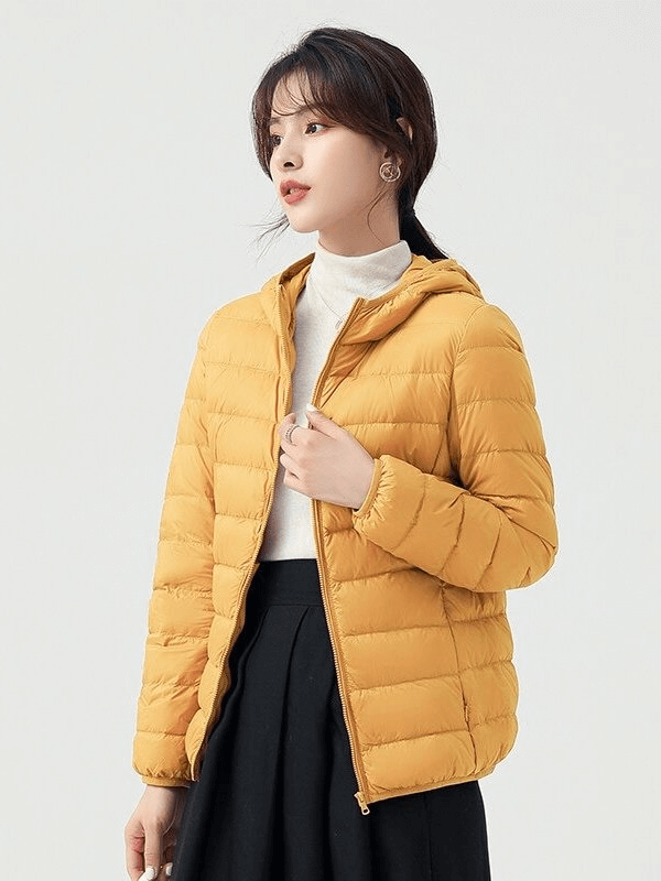 Woman wearing a stylish yellow down jacket with hood, lightweight and insulated for outdoor activities. SF0108.